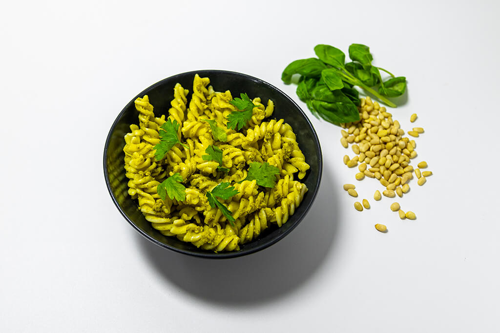 Creamy Pesto Pasta with pine nuts and herbs as decorations